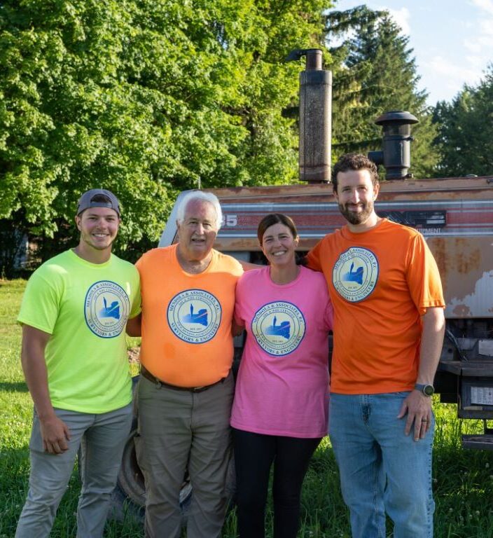 Four people standing by a tractor.